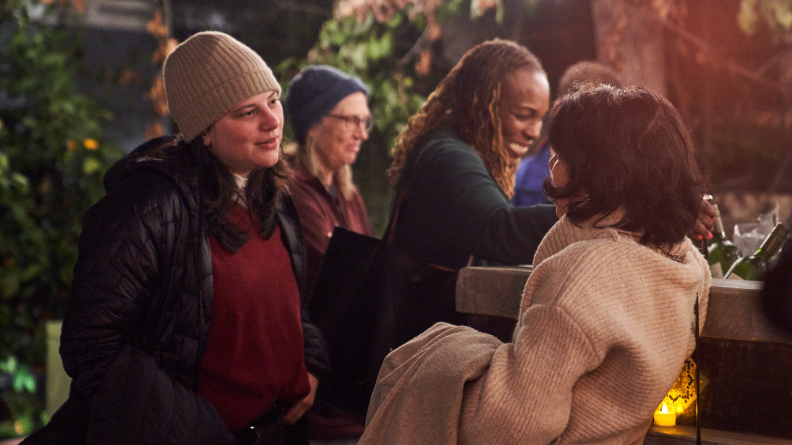 An age diverse group of women chat while getting drinks at an outdoor bar. 