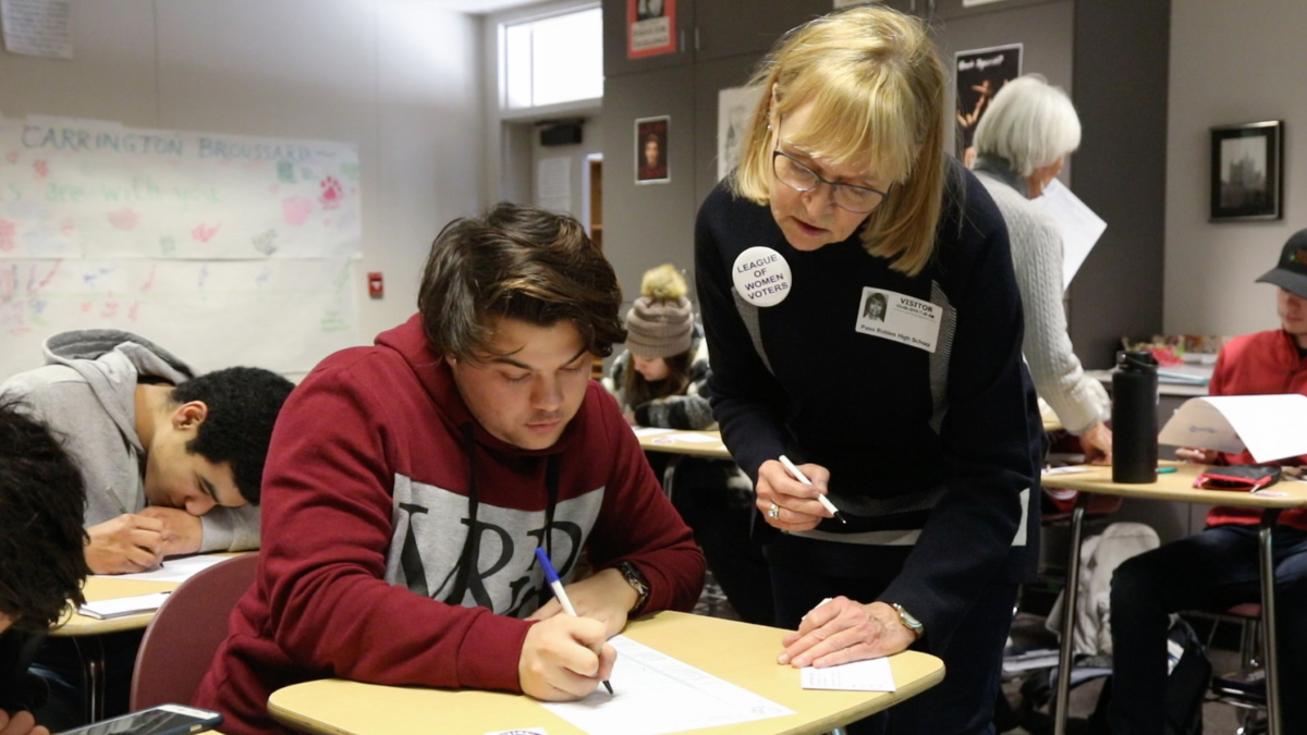 A volunteer with the League of Women Voters helps a high school student pre-register to vote.