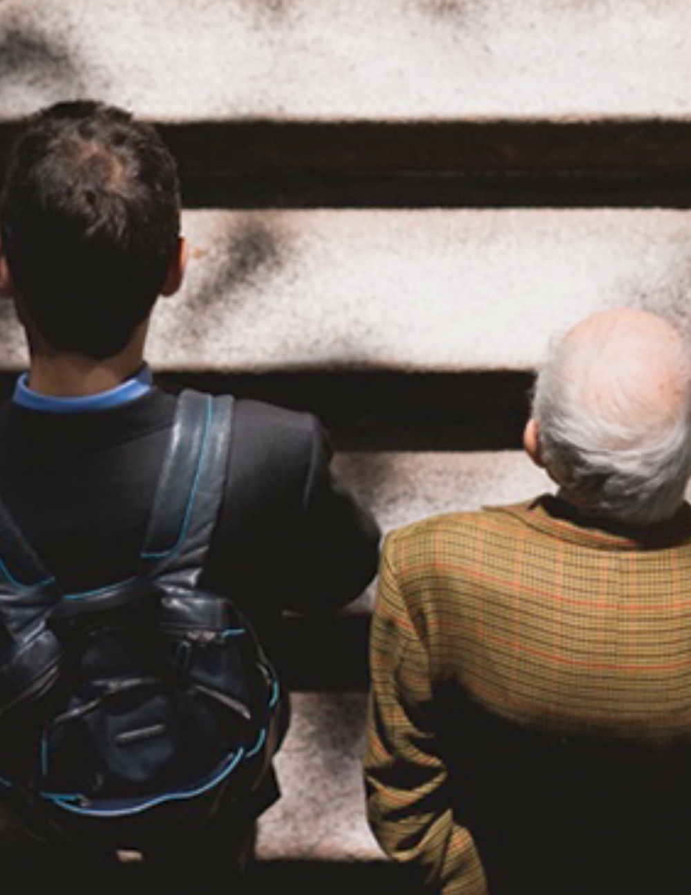 An older and younger man, photographed from above, walking up a set of stairs