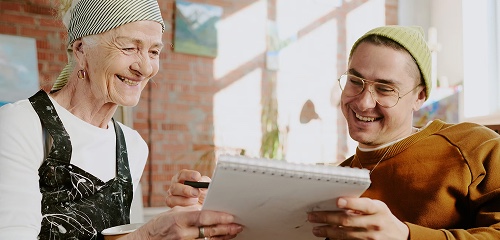 An older woman and a young man smiling at a notebook
