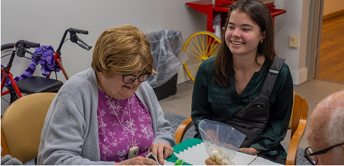 A younger and older woman smiling around a table
