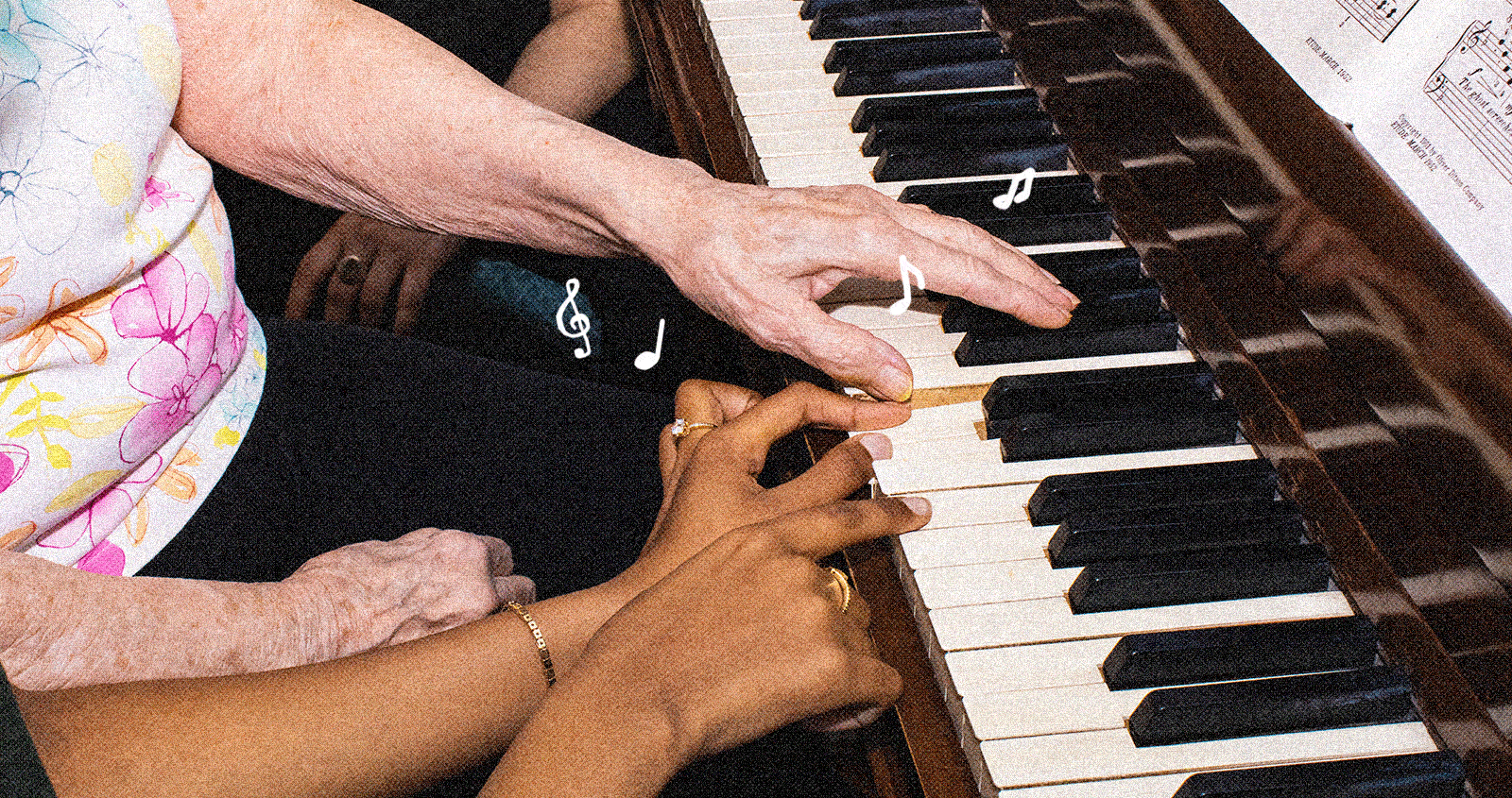 Two sets of hands, clearly older and younger, playing a piano